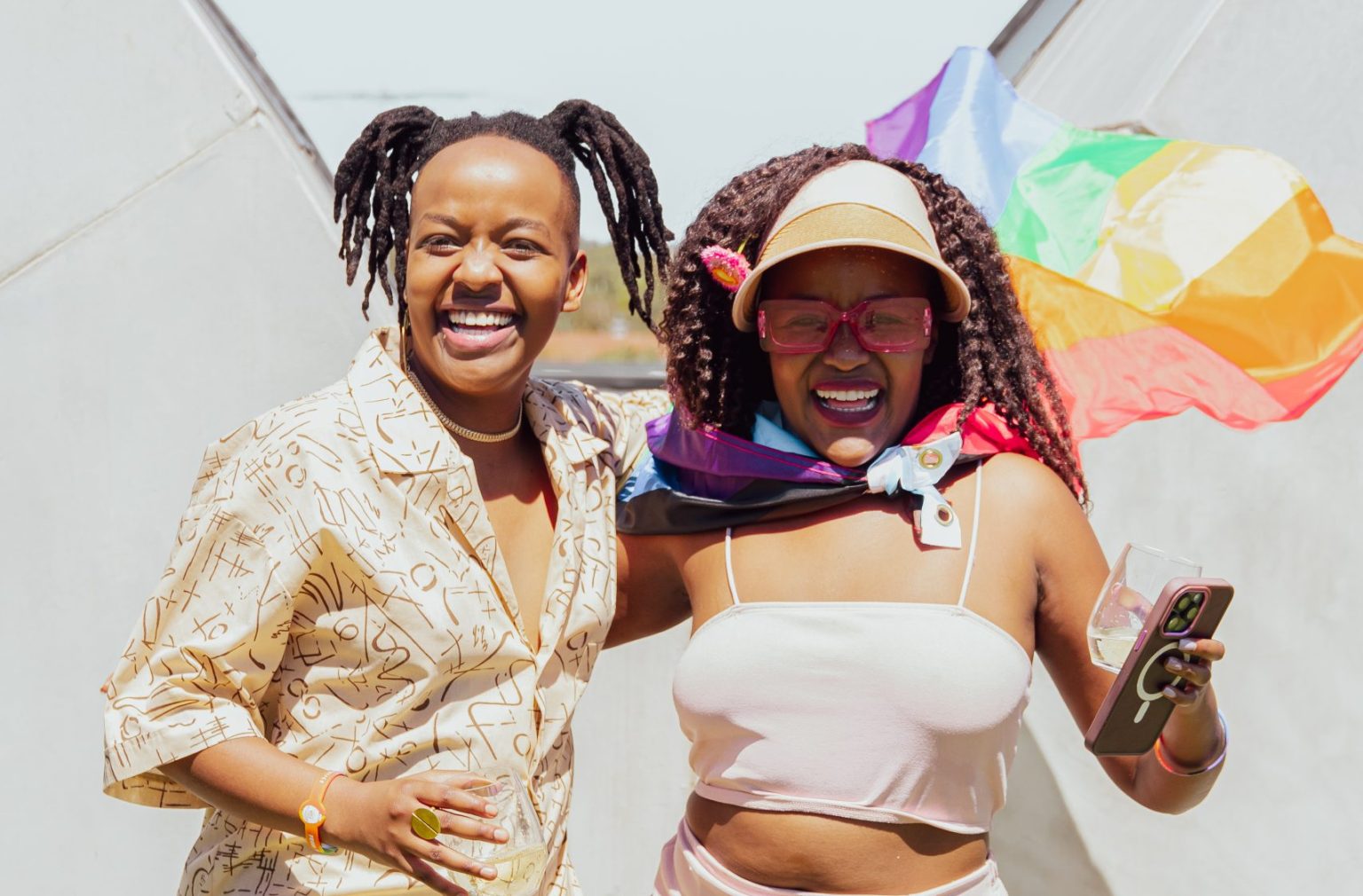 Two people smile at the camera. The sun is out, and they are drinking.