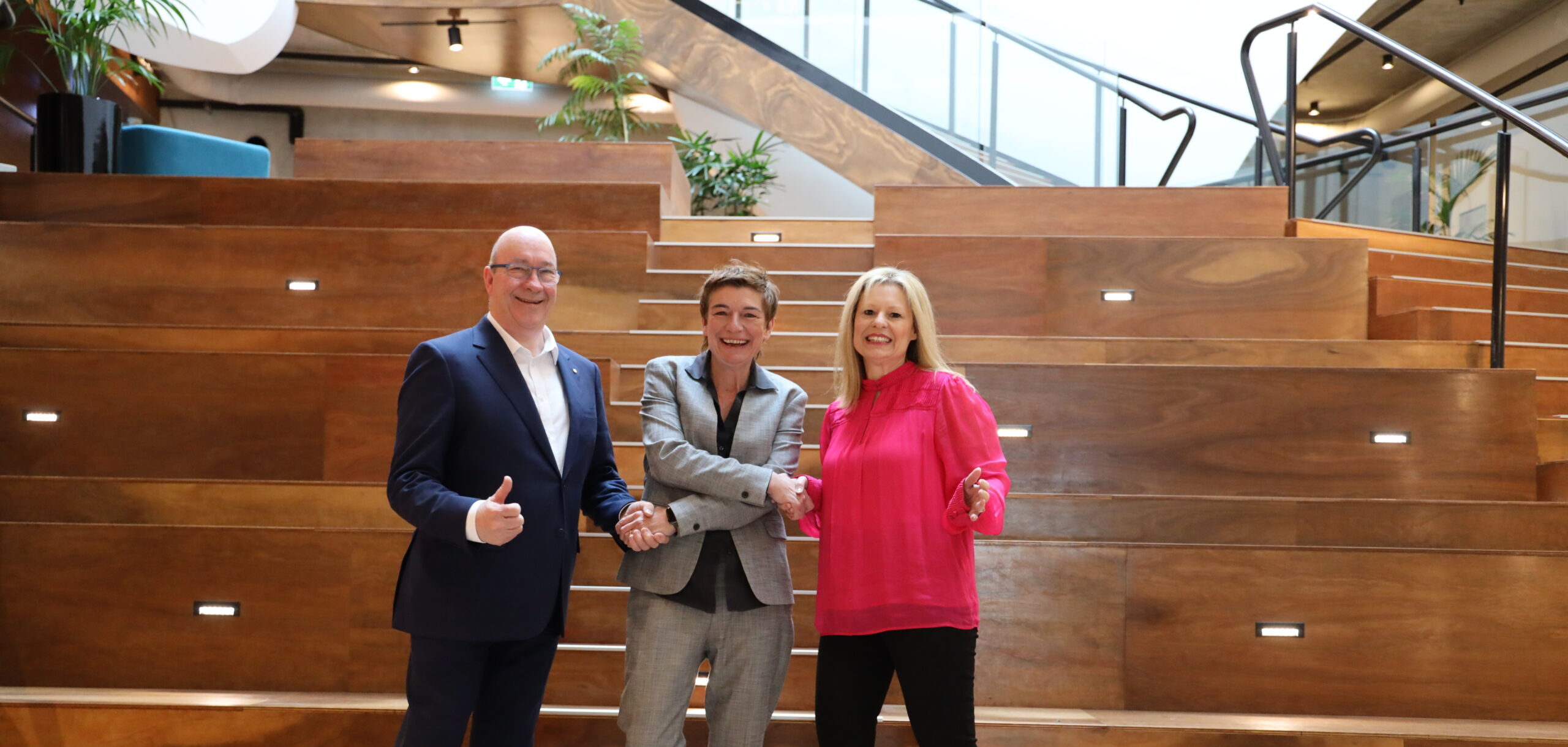 three people standing on a staircase shaking hands